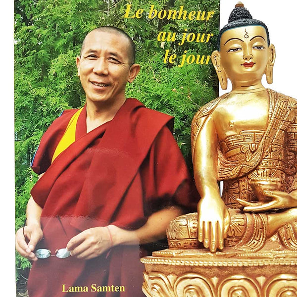 Lama Samten en robe rouge avec statue dorée de Bouddha, livre 'Le bonheur au jour le jour'