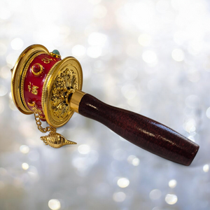Moulin à prières tibétain rouge et doré avec manche en bois, symbole bouddhiste de méditation et spiritualité
