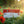 Boîte de granulés Men-Chik de la médecine tibétaine, posée sur l'herbe au soleil, fleurs rouges alentour