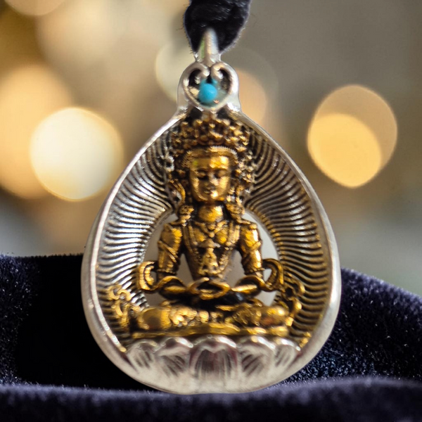 Pendentif bouddhiste en argent et or avec pierre turquoise, représentant une divinité méditative, symbole de la philosophie tibétaine.